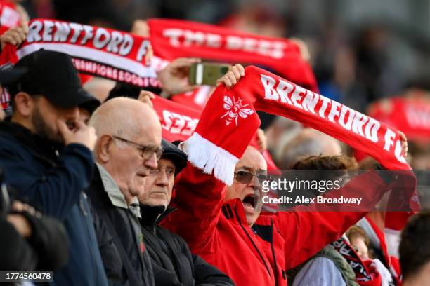 Fans of Brentford show their support as they hod scarves prior to the Premier League match between Brentford FC and West Ham United at Gtech...