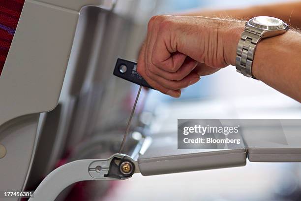 An employee uses a tool to adjust the passenger tray of a Recaro CL3510 economy class aircraft seat on the production line inside Recaro Aircraft...