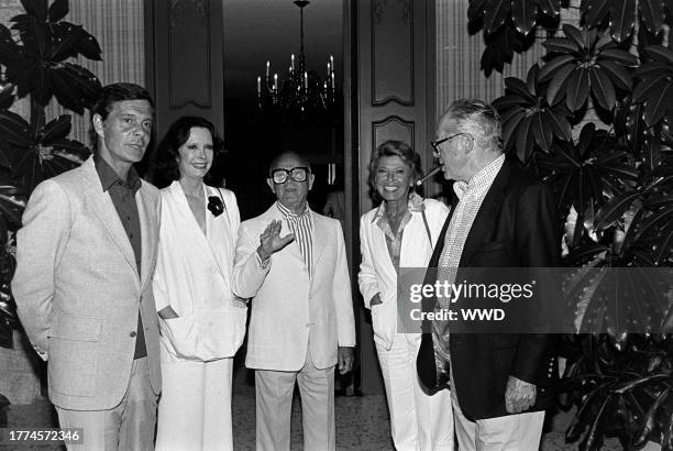 Louis Jourdan, Audrey Wilder, Irving "Swifty" Lazar, Berthe Jourdan, and Billy Wilder attend a party at the Lazar residence in Los Angeles,...