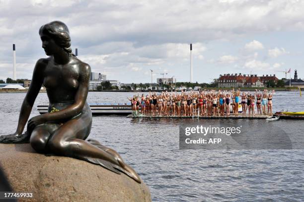 Girls prepare to jump in the water behind Copenhagen's landmark "Little Mermaid" at Langelinie in Copenhagen, on August 23, 2013 as the statue...