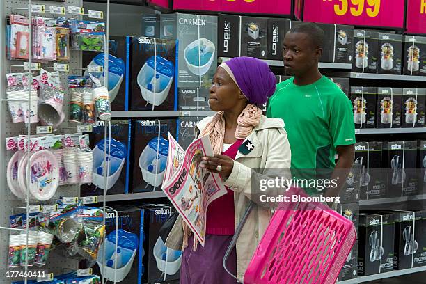 Customer carries a newspaper advertising special offers as she browses electronic goods for sale inside a Game supermarket, part of Massmart Holdings...