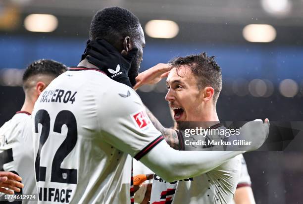 Alex Grimaldo of Bayer Leverkusen celebrates with teammate Victor Boniface after scoring the team's third goal during the Bundesliga match between...