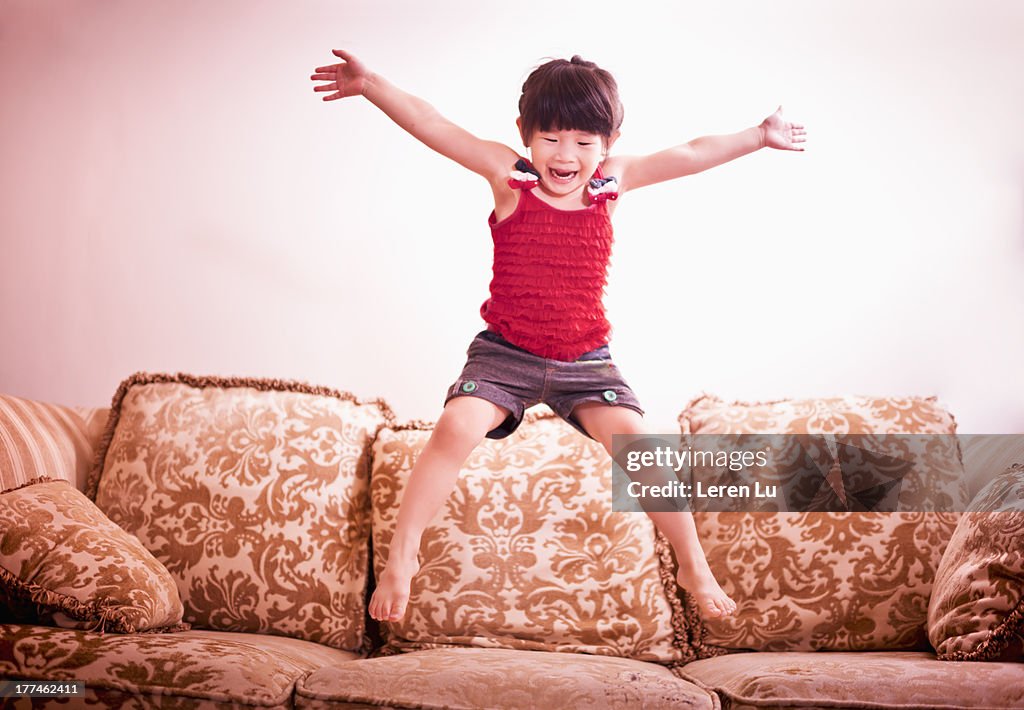 Little girl jumping on the sofa