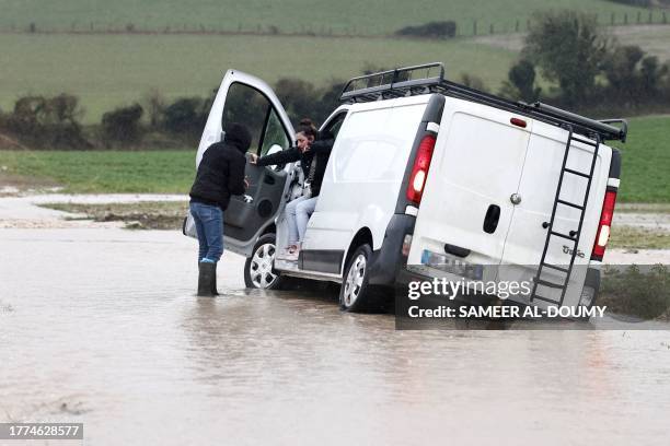 Woman is helped from a stranded van on a flooded road near the village of Verlincthun, in northern France, on November 10, 2023. The Pas-de-Calais...