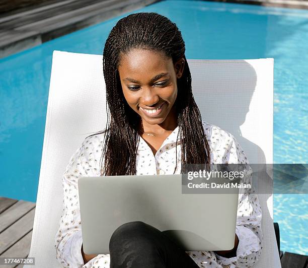 young woman using a laptop at the poolside - using laptop outside stock pictures, royalty-free photos & images