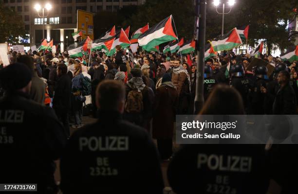 Police watch as people chant slogans and carry Palestinian flags as they arrive at Potsdamer Platz during a "Freedom for Palestine" protest march...