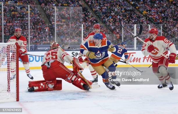 Adam Erne of the Edmonton Oilers pursues the play behind the net as Noah Hanifin, Yegor Sharangovich and MacKenzie Weegar of the Calgary Flames...