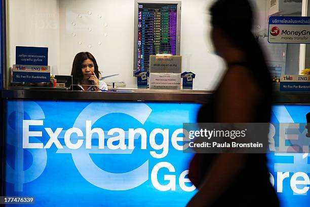 Woman sits in a money exchange bank kiosk on August 23, 2013 in downtown Bangkok, Thailand. The local currency dropped to its lowest level since...