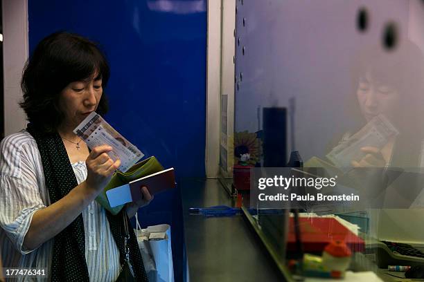 Woman staqnds near a money exchange bank kiosk on August 23, 2013 in downtown Bangkok, Thailand. The local currency dropped to its lowest level since...