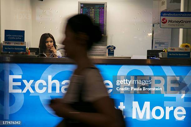 Woman looks out from a money exchange bank kiosk on August 23, 2013 in downtown Bangkok, Thailand. The local currency dropped to its lowest level...