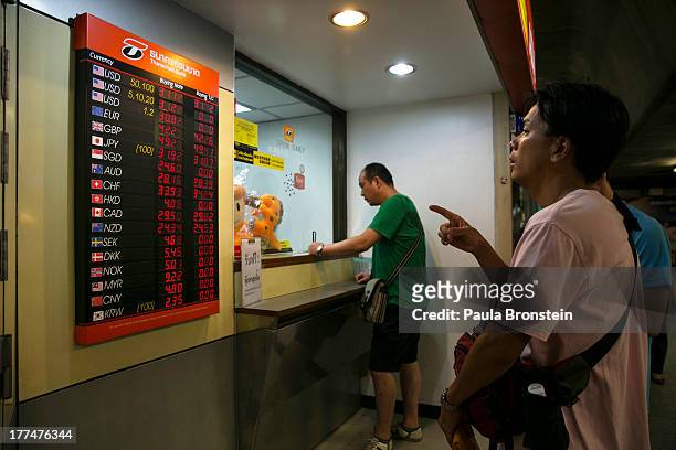 Japanese men looks at the currency board at a money exchange bank kiosk on August 23, 2013 in downtown Bangkok, Thailand. The local currency dropped...