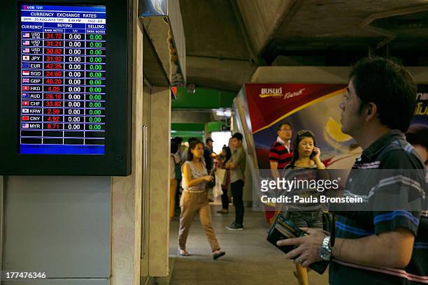 Japanese man looks at the currency board at a money exchange bank kiosk on August 23, 2013 in downtown Bangkok, Thailand. The local currency dropped...