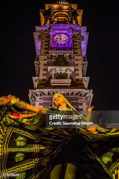 Young lady is performing with Rajasthani folk song under the clock tower during Marwar festival at Jodhpur, India. She is wearing traditional...
