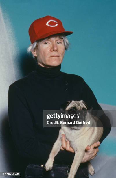 American pop artist Andy Warhol holding a pug, 1982.