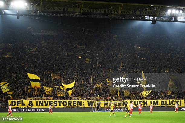 The fans of Borussia Dortmund hold a banner which reads 'DFL & investoren: wir haben euch im blick!', translating to 'DFL & investors: we have you...