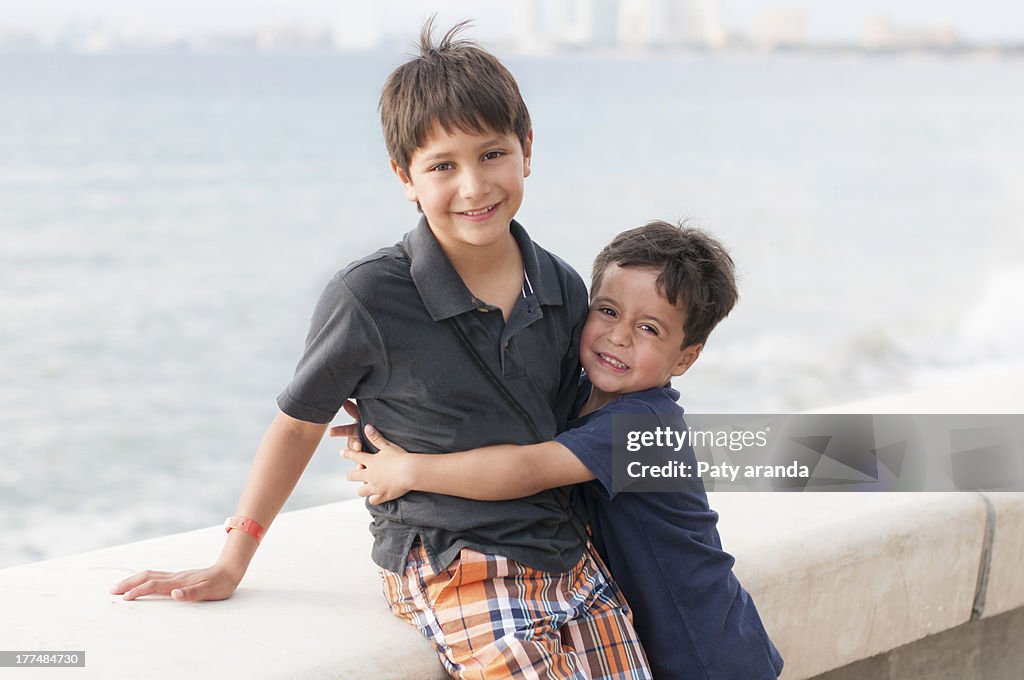 Two brothers hugging near the sea