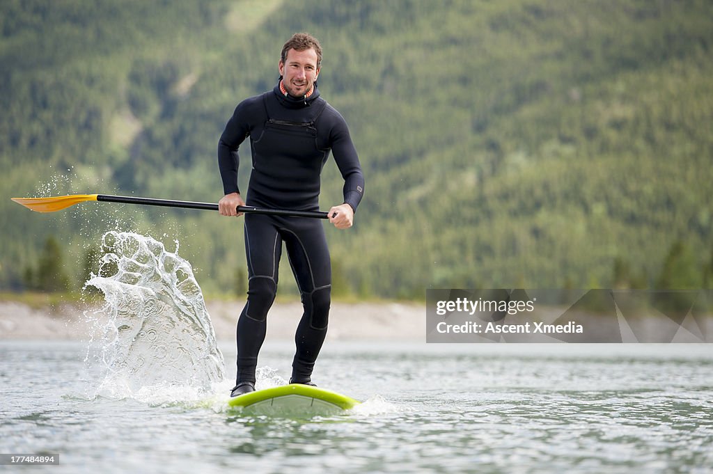 Man paddleboards across mountain lake