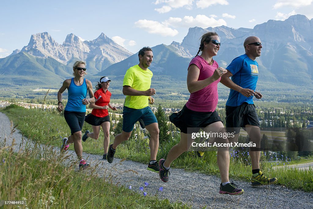 Runners race along path, in mountains