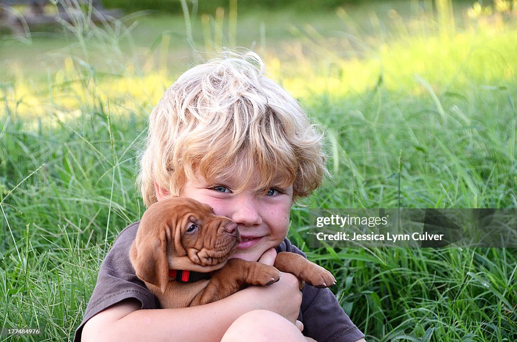 Boy with wrinkled Vizsla puppy