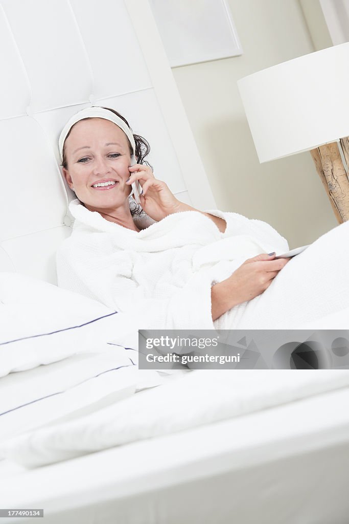 Woman in white bathrobe talking on mobile phone