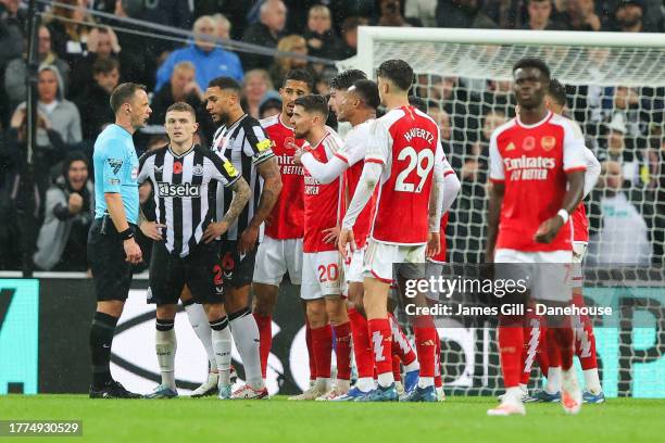 Arsenal players surround referee Stuart Atwell after Newcastle United score their first goal during the Premier League match between Newcastle United...
