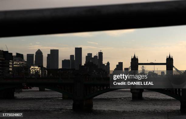 Tower Bridge , and skyscraper buildings in the Canary Wharf financial district , are pictured beyond the River Thames in London on November 10, 2023....