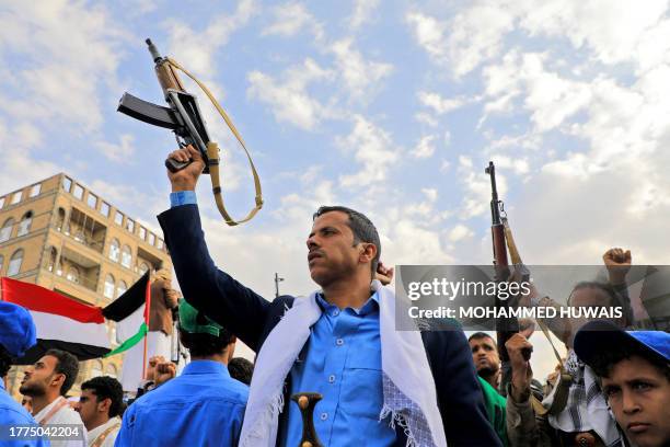 Yemenis brandish rifles and wave Palestinian flags during a march in solidarity with the people of Gaza on November 10 in the Houthi-controlled...