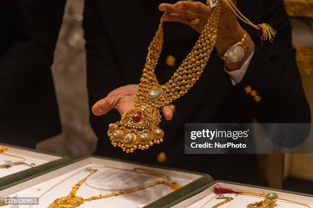 Salesman shows a gold ornament to a customer at a jewellery store on the Hindu festival of Dhanteras, a day considered auspicious to buy jewellery,...