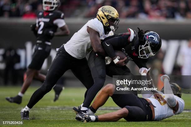 Emory Jones of the Cincinnati Bearcats carries the ball as he is tackled by Jason Johnson of the UCF Knights and Kam Moore in the second half at...
