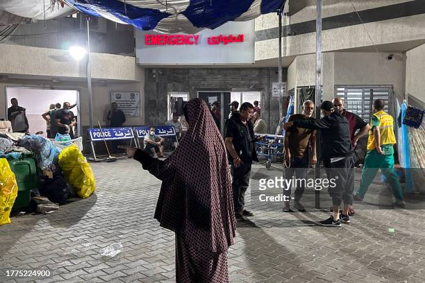 People stand outside the emergency ward of Al-Shifa hospital in Gaza City on November 10 amid ongoing battles between Israel and the Palestinian...