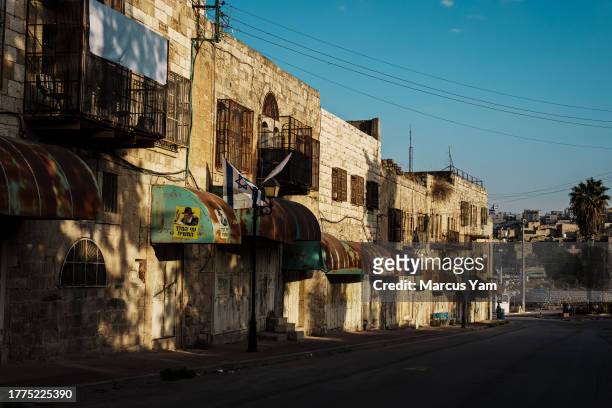 Silence resides over desolate Al-Shuhada Street, or also known as King David Street by local Israeli settlers, where Palestinian windows are caged...