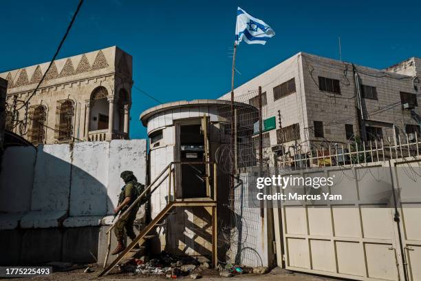 An Israeli soldier steps away from a checkpoint pillbox and fence separating the Palestinian designated side from the Israeli settlement enclave side...