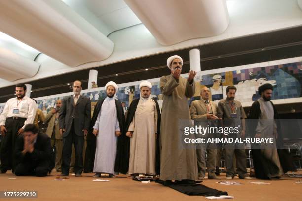 Sheikh Hussein al-Khalidi leads other delegates to the Iraqi national conference in prayer at the Baghdad convention center 17 August 2004. Delegates...