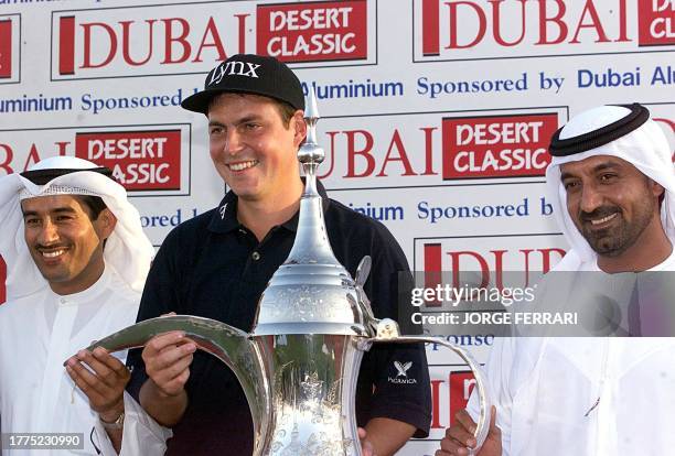 David Howell of England holds the traditional Arabic coffee pot trophy after winning the Dubai Desert Classic golf tournament 14 February, as Sheikh...