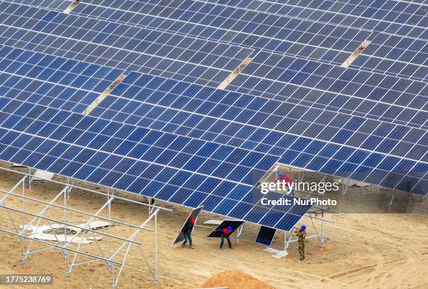 Aerial photo shows construction workers installing photovoltaic panels at a 4 million kilowatt new energy base in a coal mining subsidence area in...