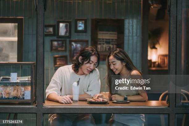 happy young asian couple dating in cafe, drinking chatting. enjoying moment together - asian couple dining stockfoto's en -beelden