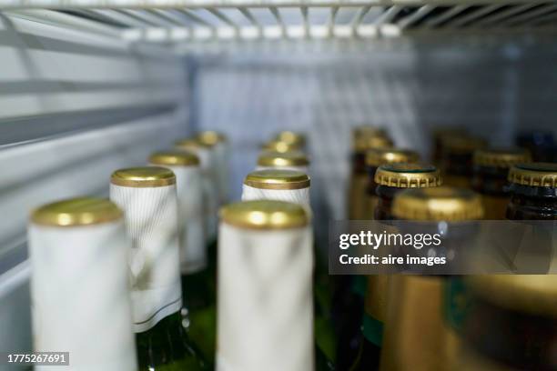 close-up of gold and white detail of beer bottles in the refrigerator compartment - beer fridge stock-fotos und bilder