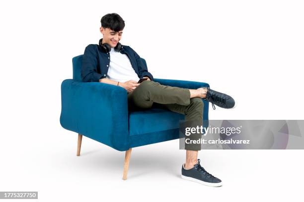 teenager texting on his phone on an armchair - armchair stock pictures, royalty-free photos & images