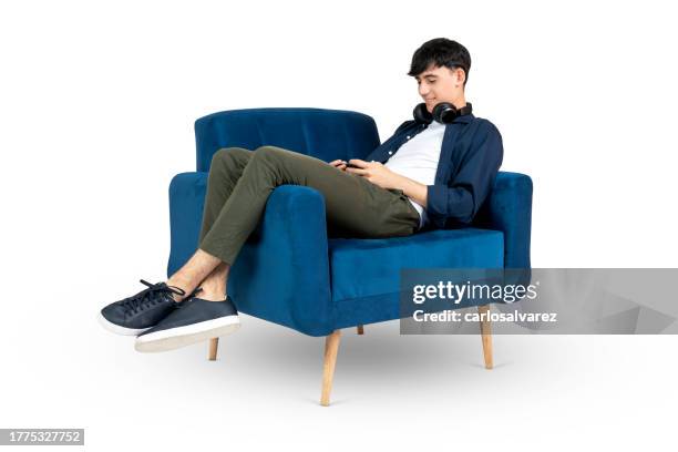teenager playing in his phone on an armchair - armchair stock pictures, royalty-free photos & images