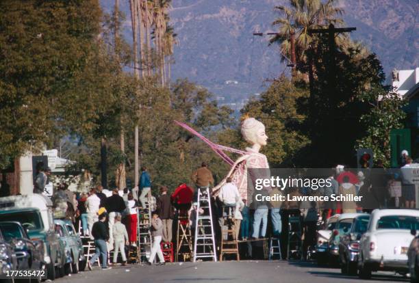 Onlookers watch, some on ladders, passing floats at the Tournament of Roses Parade, Pasadena, California, 1966.