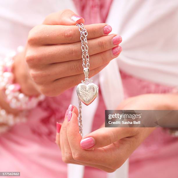 female hands holding heart locket - heart locket stock-fotos und bilder