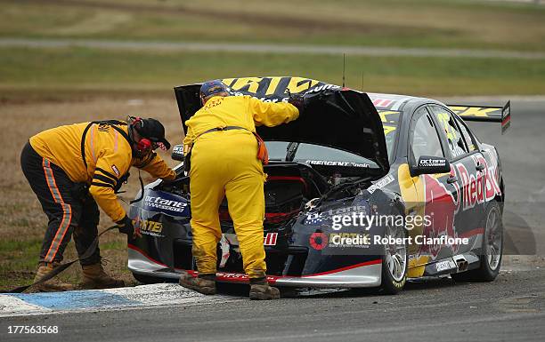 Officials look to remove the Red Bull Pirtek Holden of Casey Stoner from the track after crashing out at the start of race five of the Dunlop...