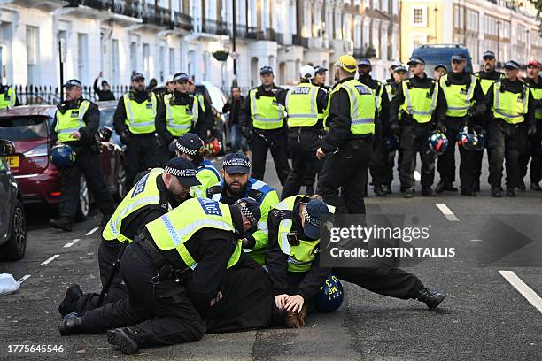 Police officers detain a man in the street close to the 'National March For Palestine' in central London on November 11 as counter-protest groups are...