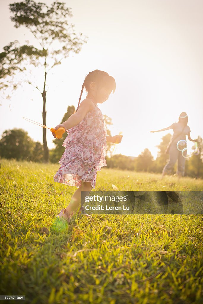 Child playing bubbles under sunset