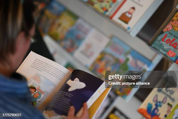 November 2023, Lower Saxony, Oldenburg: A visitor reads newly published children's books at the 49th Children's and Young Adult Book Fair. The 49th...