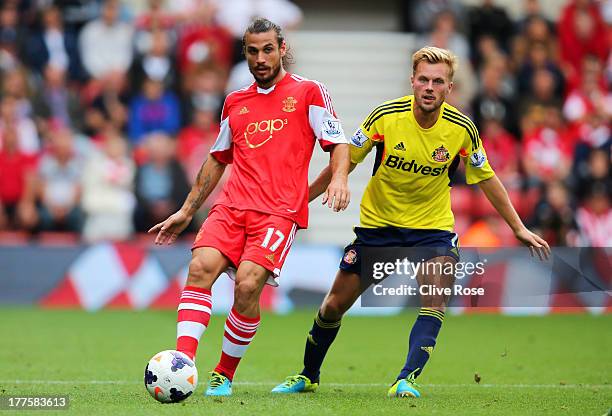 Daniel Osvaldo of Southampton passes the ball as Sebastian Larsson of Sunderland closes in during the Barclays Premier League match between...