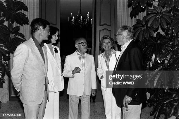 Louis Jourdan, Audrey Wilder, Irving "Swifty" Lazar, Berthe Jourdan, and Billy Wilder attend a party at the Lazar residence in Los Angeles,...