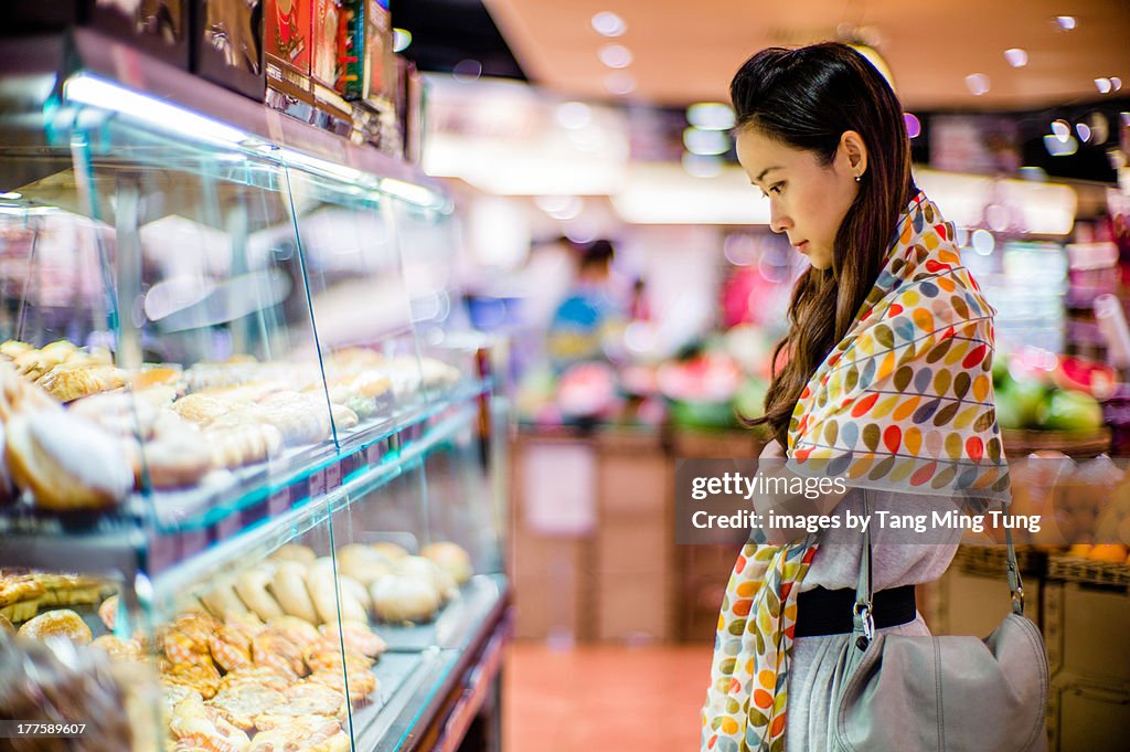 Young lady looking at supermarket's bakery display
