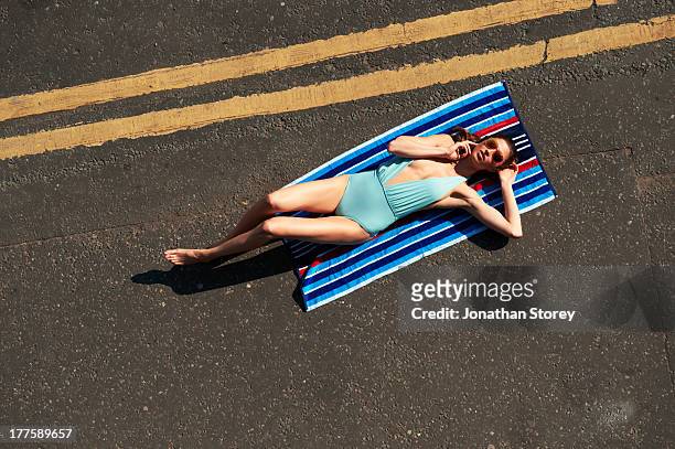 sunbathing road - beach towel stockfoto's en -beelden