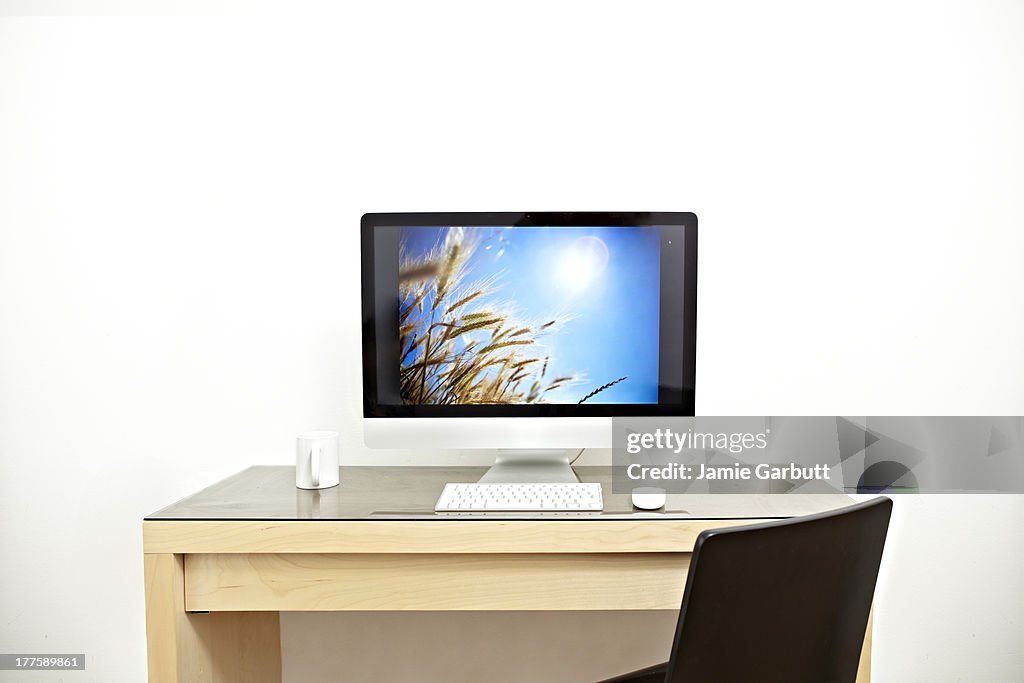 Computer on a desk with a white mug